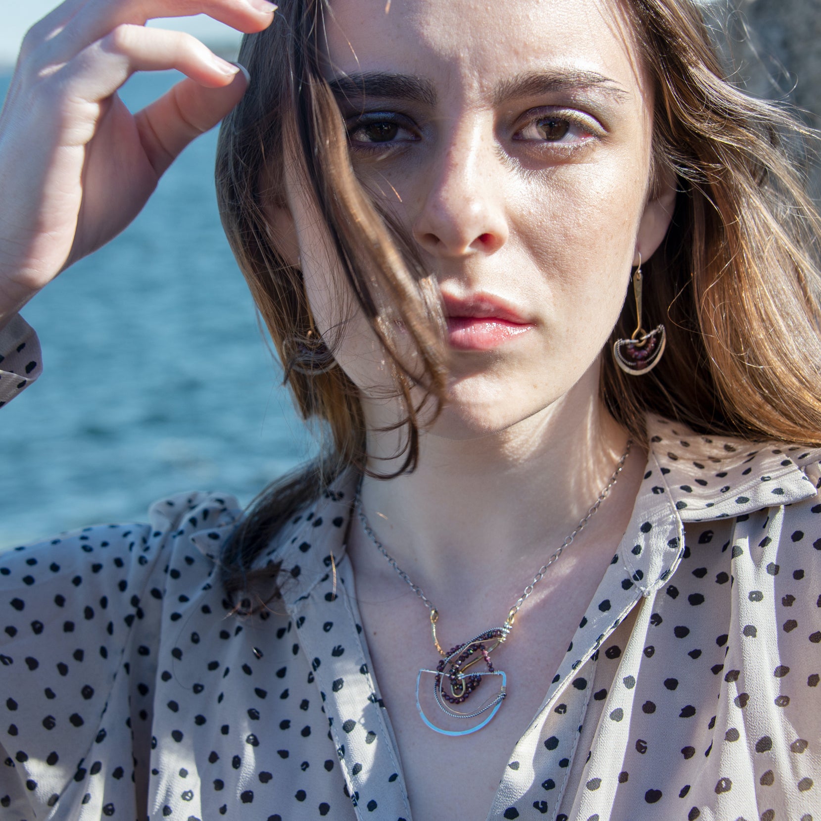Faceted garnet gemstones braided within a sterling silver and brass fan necklace with oxidized sterling twisted wire on a delicate darkened chain