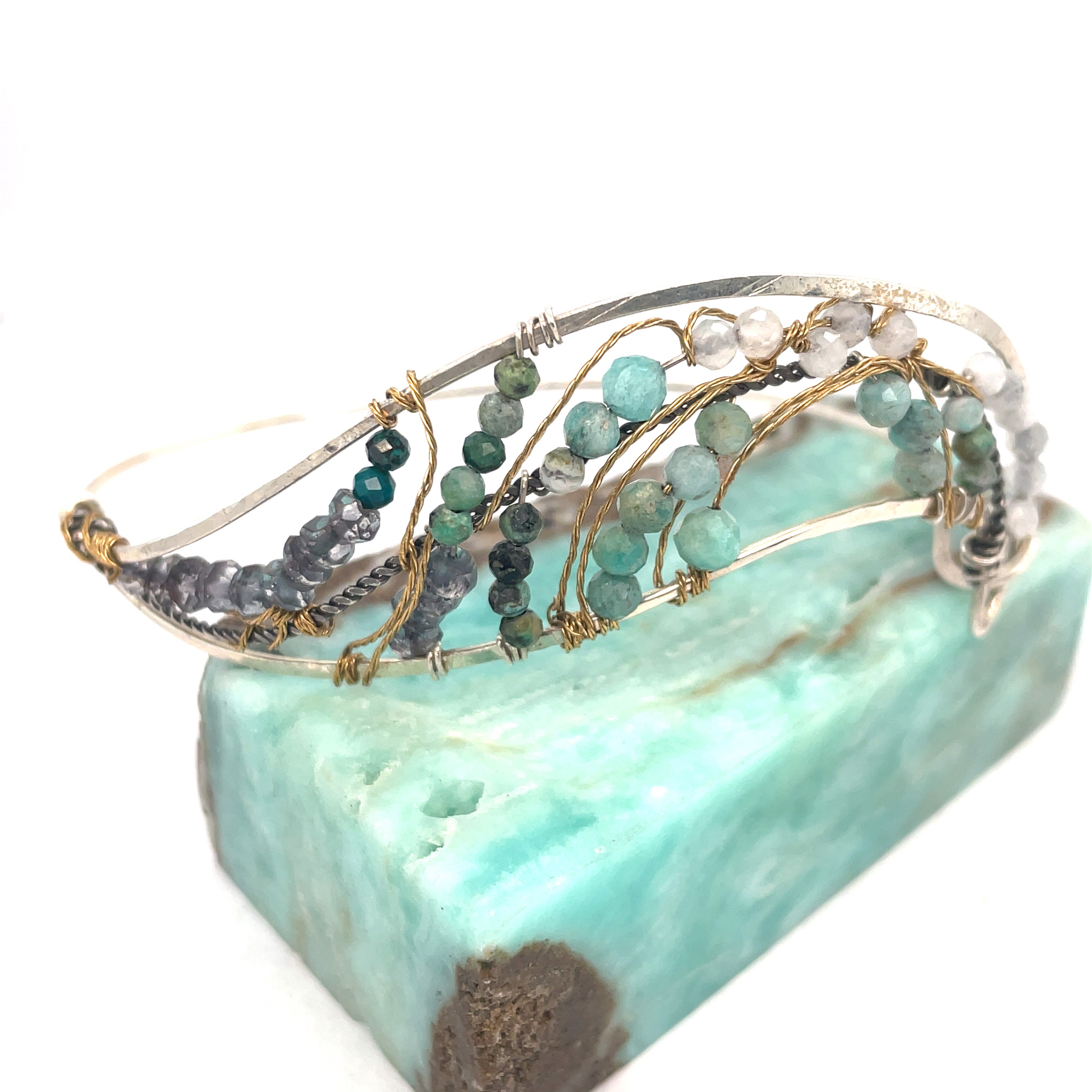 Amazonite, chrysocolla, blue quartz, and moonstone gemstones held within a handmade sterling silver wave shaped bracelet with oxidized twist, gold filled, and brass wire accents
