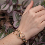 moss agate, green amethyst, and crystal gemstones are braided within waves of hammered brass, bronze, and sterling silver to form a braided cuff bracelet