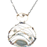 A basket weaved darkened sterling silver and brass pendant necklace featuring a flashy labradorite marquise and blue crystal accents on gold filled wire 