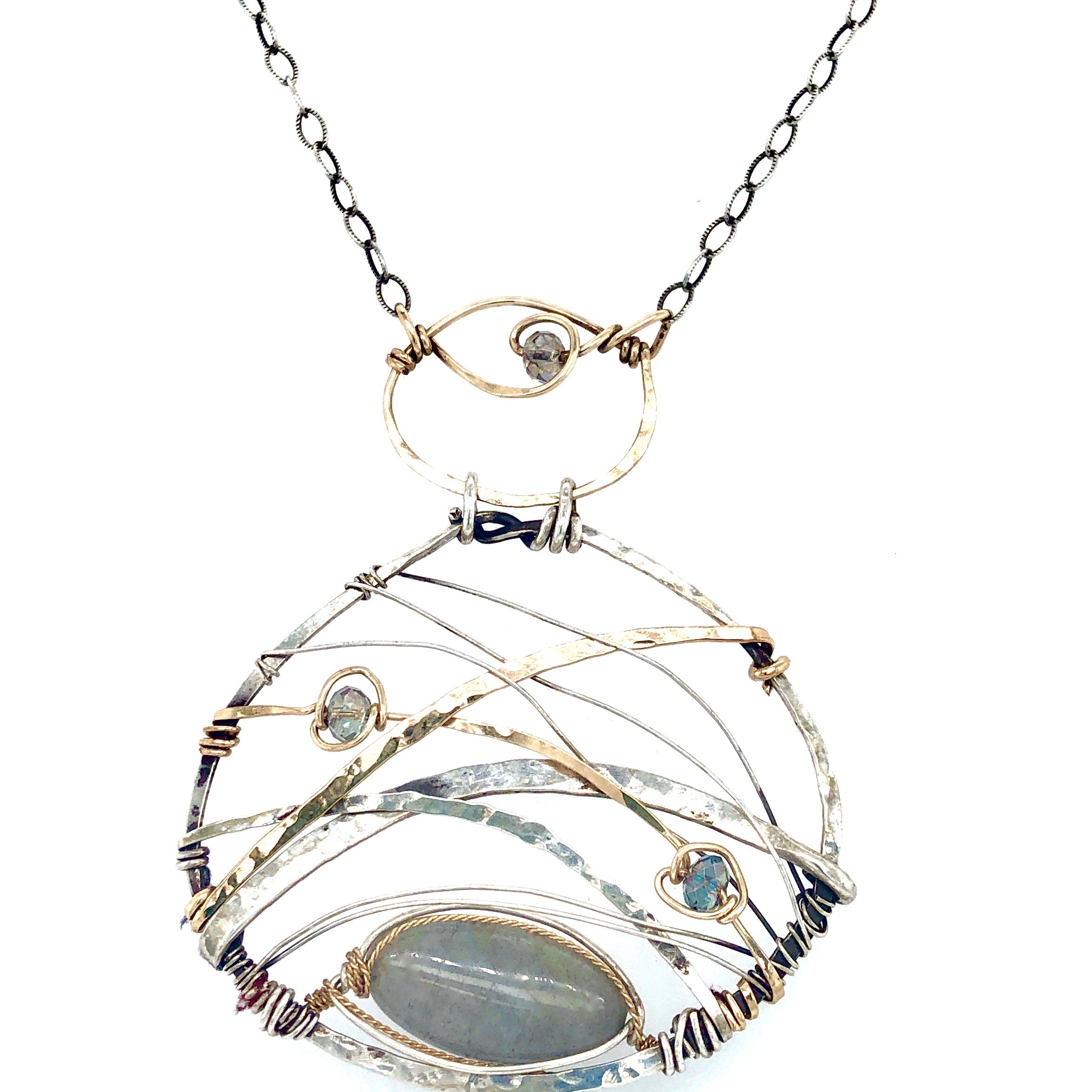 A basket weaved darkened sterling silver and brass pendant necklace featuring a flashy labradorite marquise and blue crystal accents on gold filled wire 