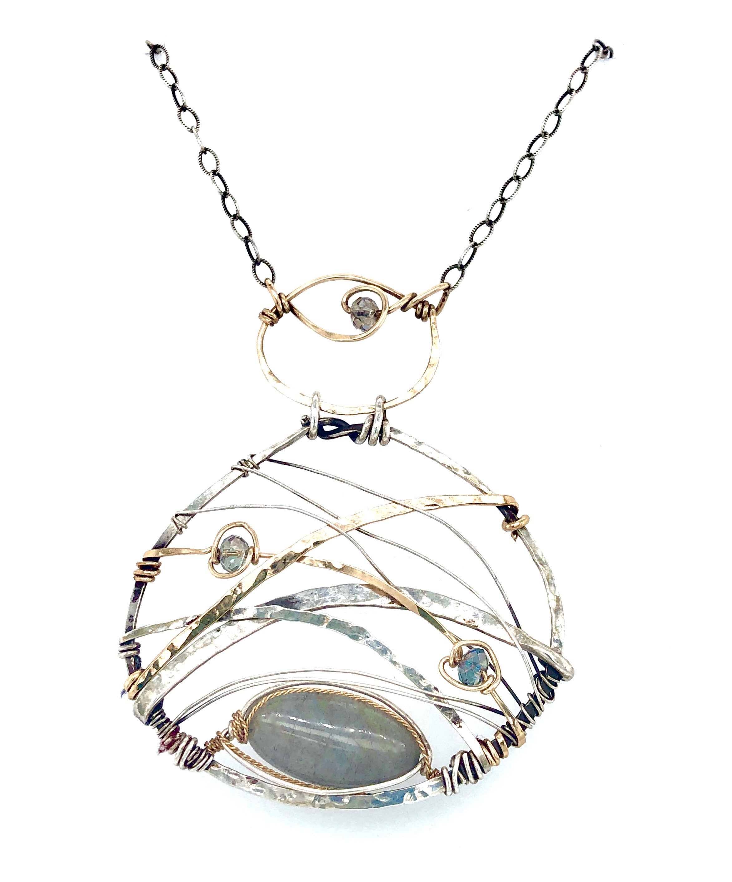 A basket weaved darkened sterling silver and brass pendant necklace featuring a flashy labradorite marquise and blue crystal accents on gold filled wire 