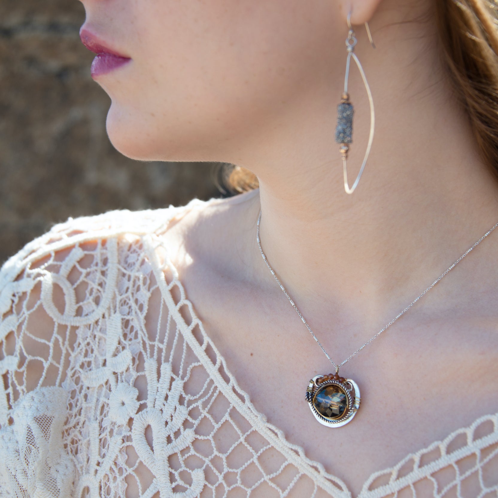 a metallic silver and gold crystal pendant necklace with a geometric design, with hessonite garnet accent and a sparkly sterling silver chain