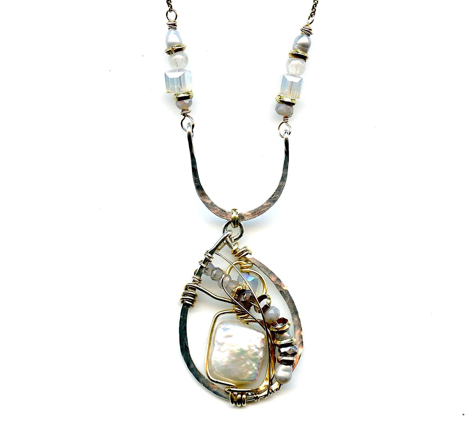 Fresh water pearl tile surrounded by labradorite, crystal, brass, and silver pearl gemstones in a handmade hammered sterling silver drop hanging from a sterling arch. 