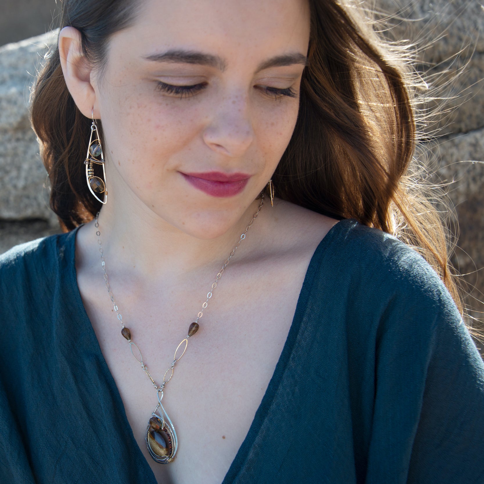 Petrified wood, smokey quartz, and tiger's eye gemstones fill a sterling silver pendant necklace with gold fill accents