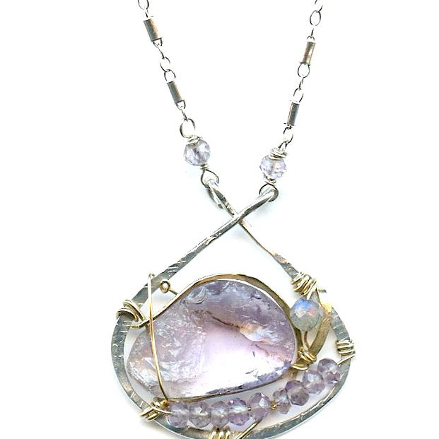 raw amethyst nugget is held in brass and gold filled wire with faceted amethyst and labradorite gemstones accents all inside a sterling silver pendant pendant