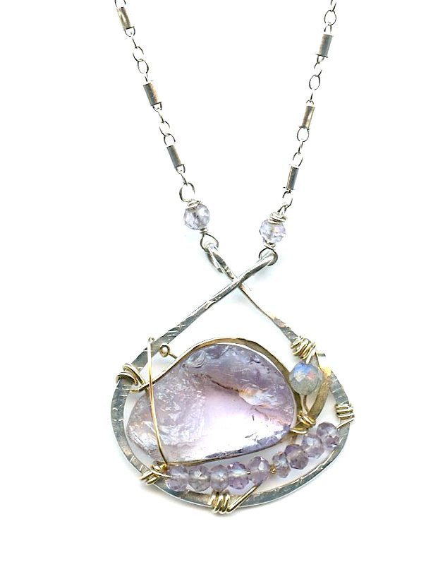 raw amethyst nugget is held in brass and gold filled wire with faceted amethyst and labradorite gemstones accents all inside a sterling silver pendant pendant