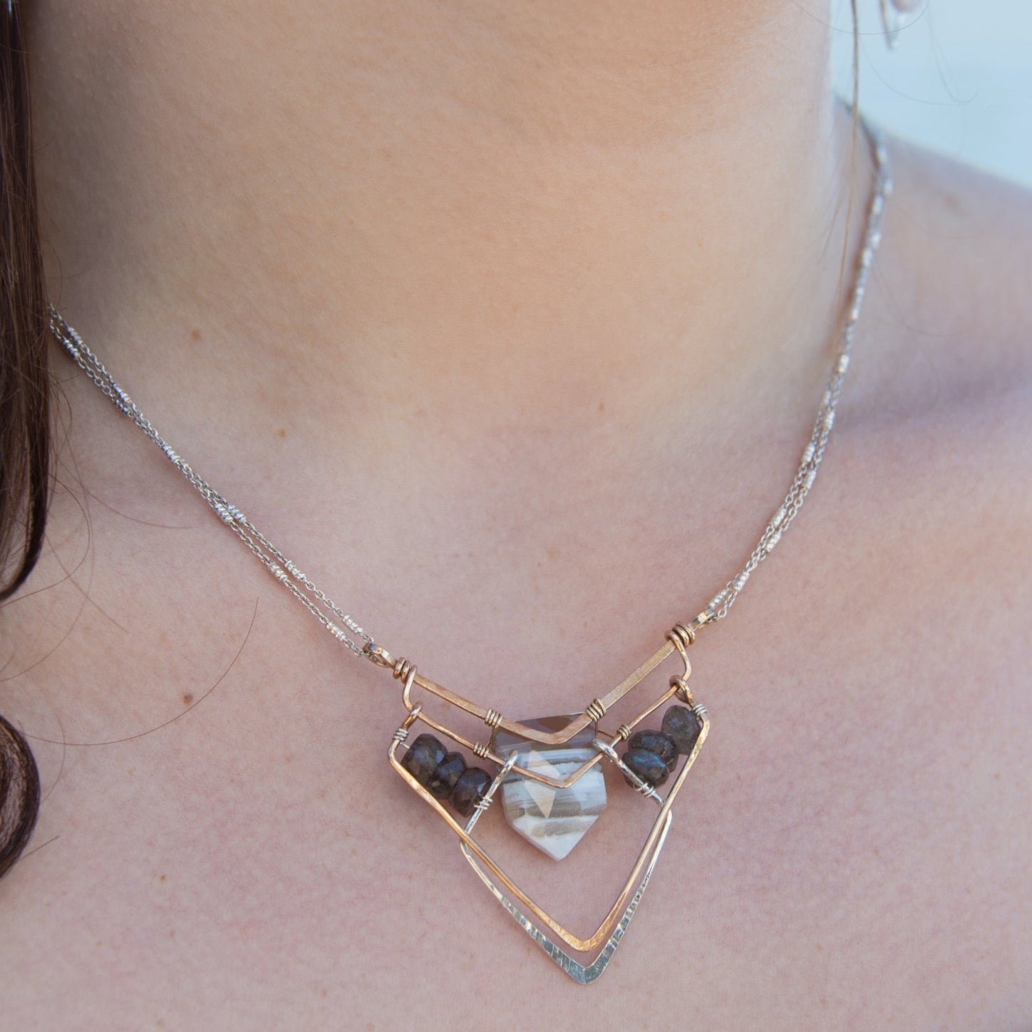 A brass and sterling silver pendant necklace featuring a blue lace agate point and faceted flashy labradorite gemstones with a doubled sterling silver sparkly chain