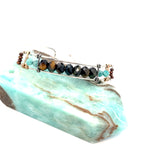 Skinny sterling silver hammered bracelet with faceted tiger's eye, amazonite, and pyrite gemstones, featuring darkened sterling silver twist and bronze hammered accents