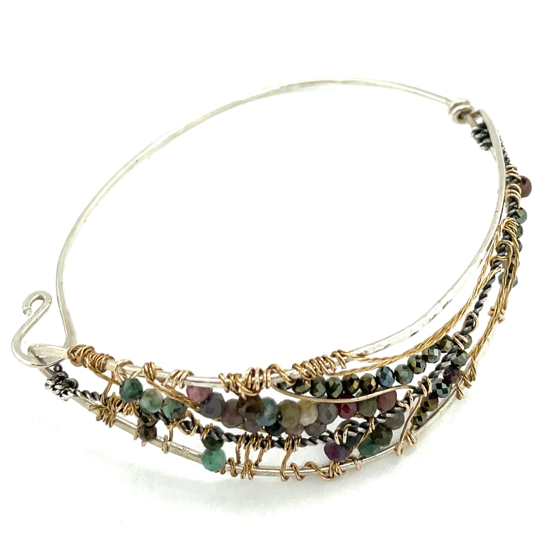 A sterling silver wave shaped bracelet embellished with faceted tourmaline and pyrite gemstones on gold filled wire and brass twist accents