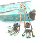 A pair of bronze triangle earrings with faceted rhomboid smokey quartz and dangles of crystal and green kyanite gemstones