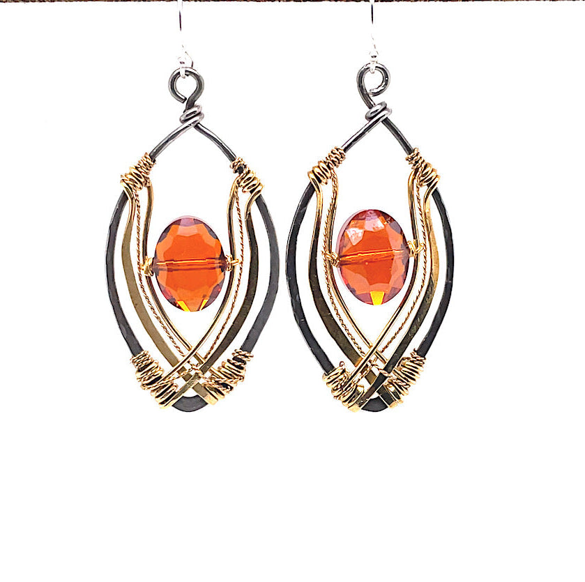 red/orange oval crystal sits inside layers of hammered brass and brass twist wire inside a darkened sterling silver marquise earring